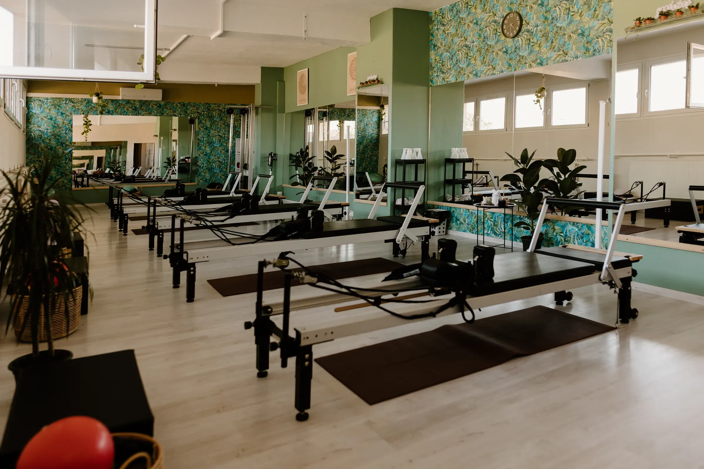 A spacious reformer room with a light floor and a row of machines